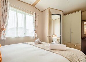 Ein Hotelzimmer mit einem großen Bett, einem Kleiderschrank, einem Badezimmer und einem Fenster mit Vorhängen.