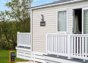 Une maison mobile dotée d’une terrasse, d’une boîte aux lettres et d’une enseigne sur laquelle on peut lire « Wimbledon ».