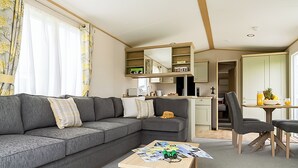 Ein kompakter Wohnbereich mit Sofa, kleinem Tisch, einer Küchenzeile und einem Essbereich.