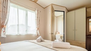 Ein Hotelzimmer mit einem großen Bett, einem Kleiderschrank, einem Badezimmer und einem Fenster mit Vorhängen.