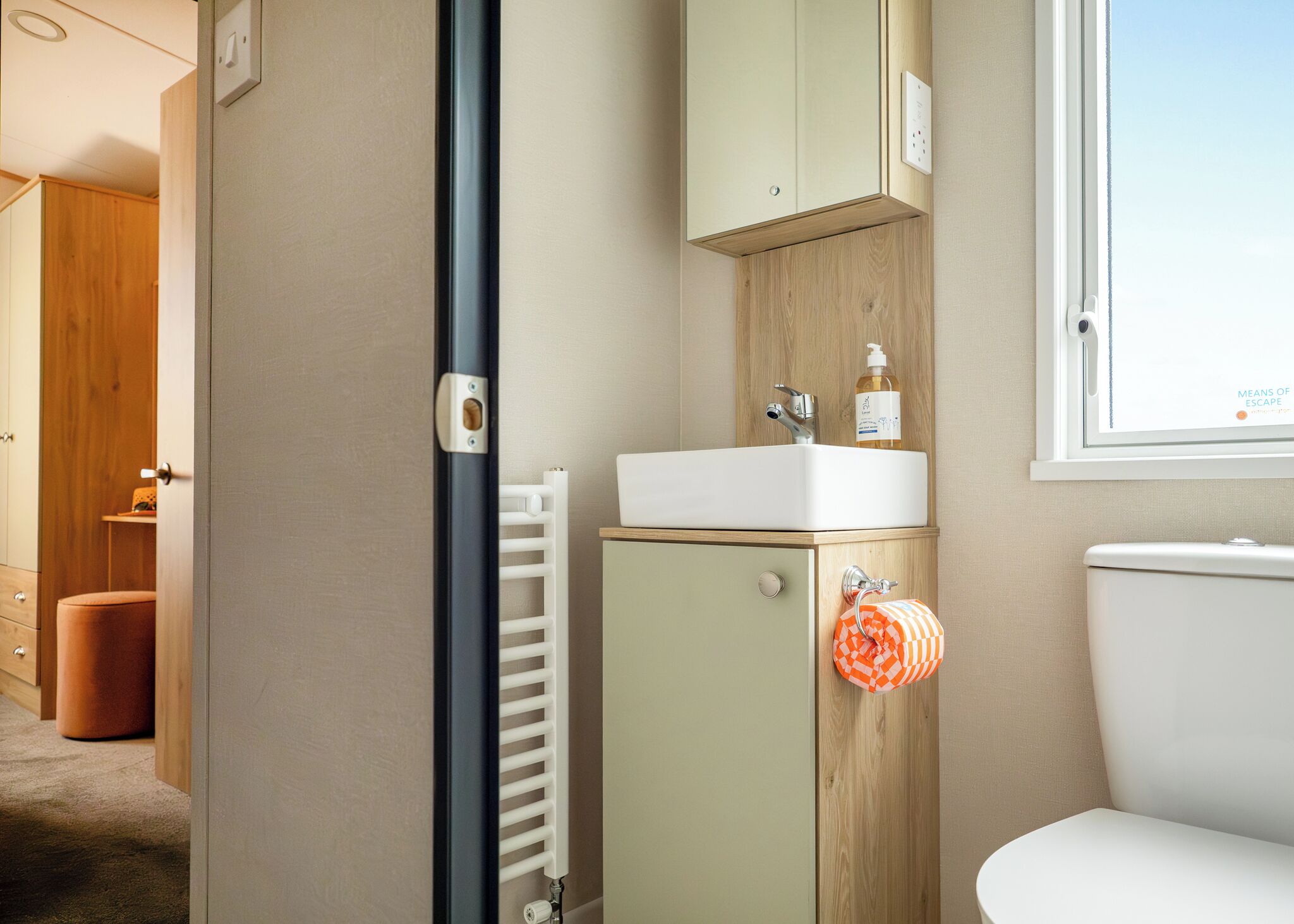 A bathroom with a white sink, wooden cabinet, and a toilet.