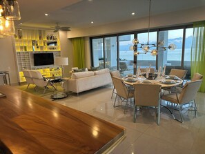 A modern living room with a dining area, a TV, and a large window with a view. - 1BR Residence at Garza Blanca Cancun 5-Star Resort (Cancún)