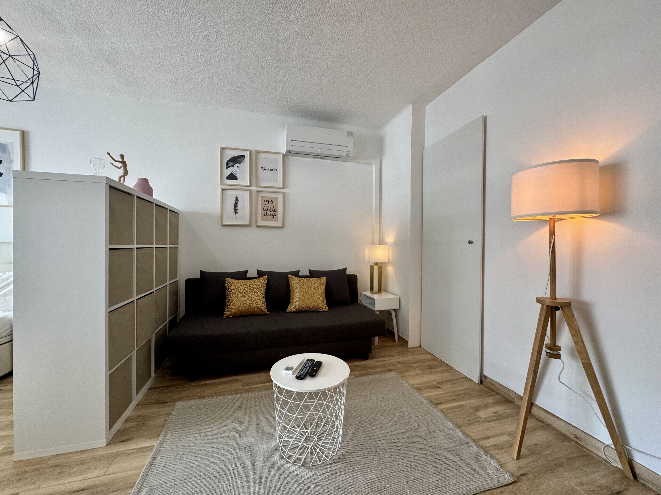 Een moderne woonkamer met een bank, een bijzettafeltje, een lamp en een klein rond tafeltje met een afstandsbediening.