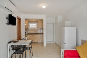A compact living space with a kitchenette, a dining area with a table and chairs, and a bed with a red and yellow pillow. - Vacation Home 'My Little Bungalow 50' with Mountain View, Wi-Fi, and Air Conditioning (Palm-Mar)