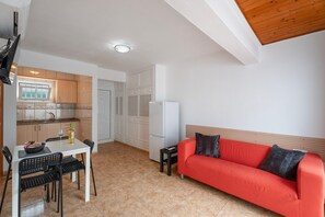 Een knus woongedeelte met een eethoek, kitchenette en een rode bank.