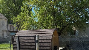 A small, fenced outdoor area with a wooden structure, possibly a shed or storage unit, and a paved access path. - Quiet cabin in the Fontainebleau forest (Oncy-sur-École)