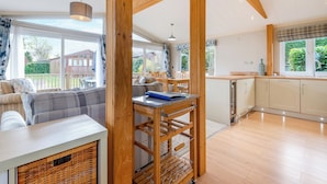 A spacious living area with a sofa, dining table, and kitchen area with wooden cabinets and a window.