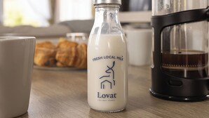 Een fles verse lokale melk, een koffiezetapparaat en gebak op een tafel.