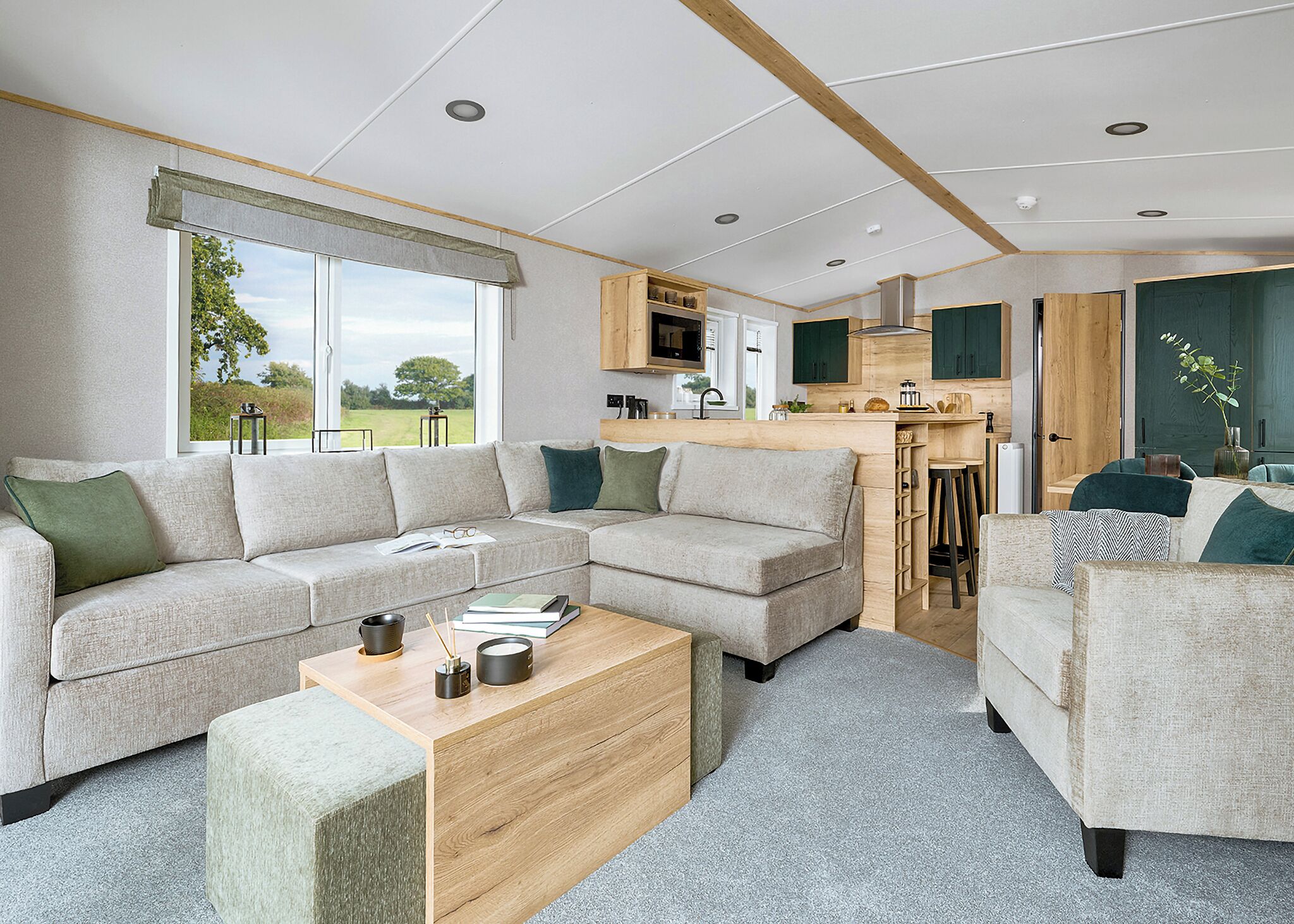 A modern living room with a sectional sofa, a wooden coffee table, and a kitchen area with bar stools.