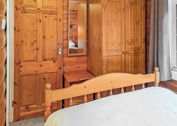 Une pièce en bois avec un lit, une armoire et un miroir.