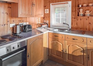 Une cuisine en bois équipée d’une cuisinière, d’un grille-pain, d’une bouilloire, d’un évier et de placards.