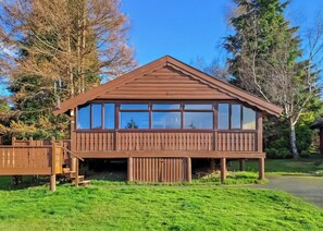 Une cabane en bois dotée d’un balcon, de grandes fenêtres et d’une terrasse.