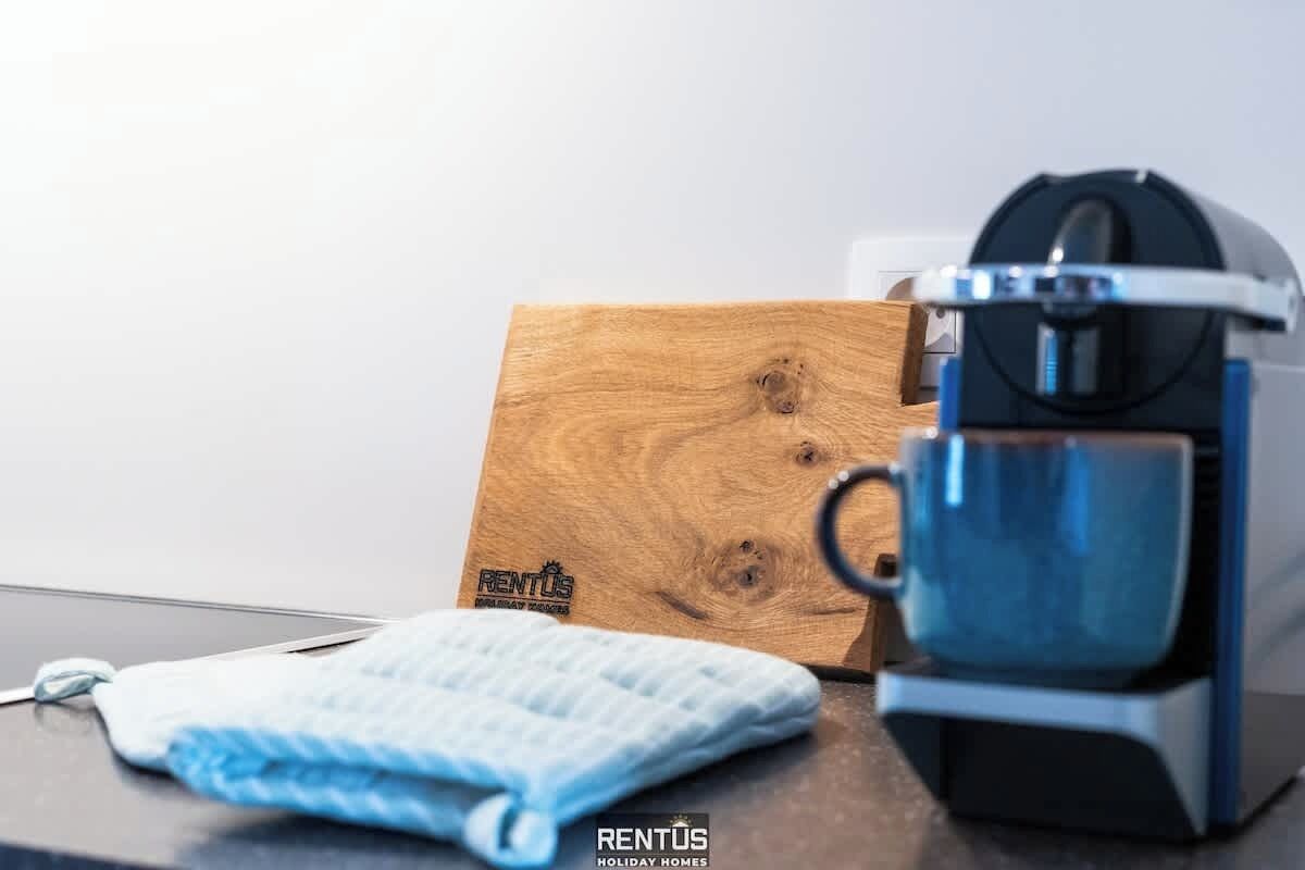 A coffee maker, a blue mug, a wooden box, and a blue towel on a table.