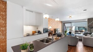 Une cuisine moderne dotée d’un îlot central, un coin repas avec une table et des chaises, et un salon avec un canapé.