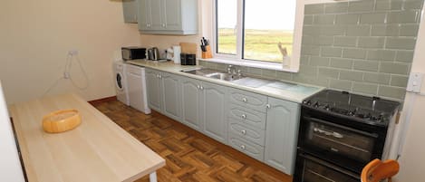 A kitchen with a washing machine, a sink, a stove, and a window with a view.