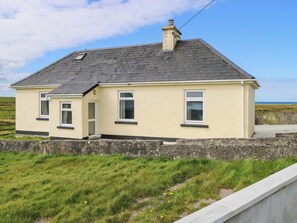 A single-story house with a gabled roof, a chimney, and a small porch. - OCEAN VIEW, pet friendly, with open fire in Louisburgh, County Mayo (Westport)