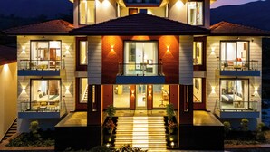 Una casa de varios pisos con un balcón, una escalera y una entrada bien iluminada.
