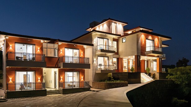 Un edificio residencial de varios pisos con balcones, ventanas amplias y una entrada bien iluminada.