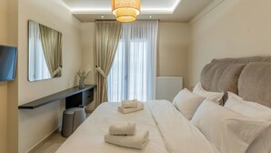 Una habitación de hotel moderna con una cama grande, un televisor de pantalla plana, una mesita de noche y un ventanal con cortinas.
