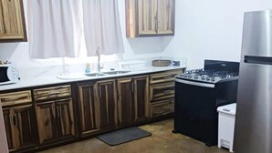 Eine Küche mit Holzschränken, einem Edelstahlkühlschrank, einem Gasherd und einer Mikrowelle.