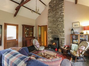 A cozy living room with a stone fireplace, wooden furniture, and a bookshelf. - Tyn Y Fron (Llanon)