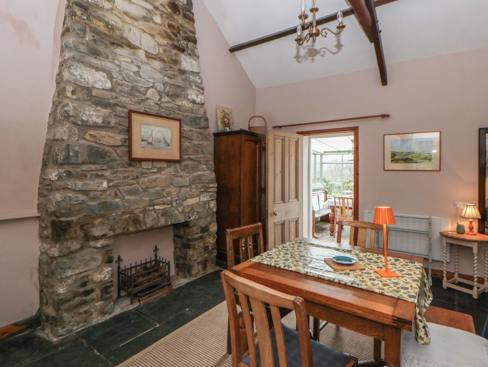 Un comedor con pared de piedra, mesa de madera, sillas y un candelabro.