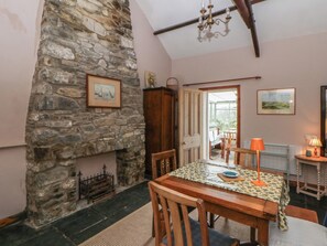A dining area with a stone wall, wooden table, chairs, and a chandelier.