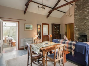 A dining area with a table and chairs, a sofa, a fireplace, and a stone wall.