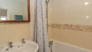 A bathroom with a sink, mirror, shower, and tiled walls.