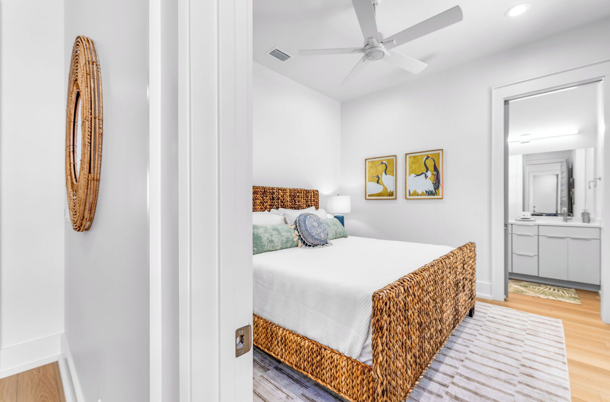 A bedroom with a bed, a ceiling fan, a wall-mounted lamp, and two framed pictures.