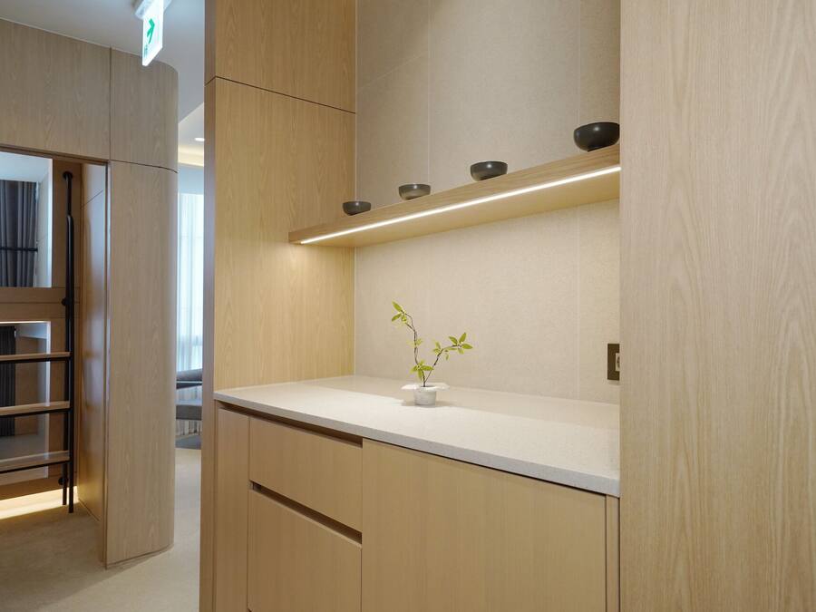 A modern interior with wooden cabinetry, a white countertop, and a small potted plant.