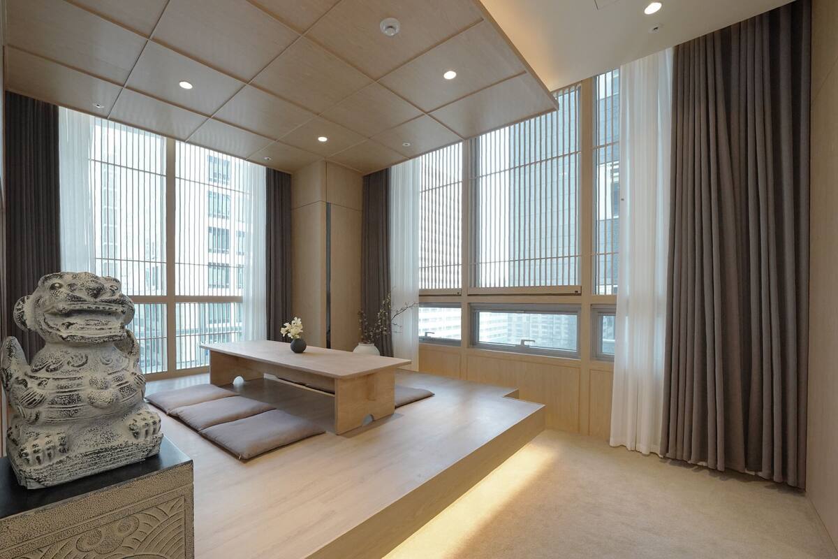 A modern interior with a wooden desk, cushioned seating, and a decorative stone sculpture.