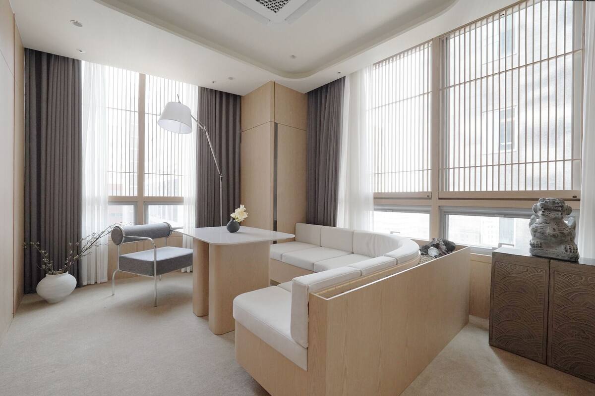A modern living room with a sofa, a small table, a lamp, and a decorative statue.