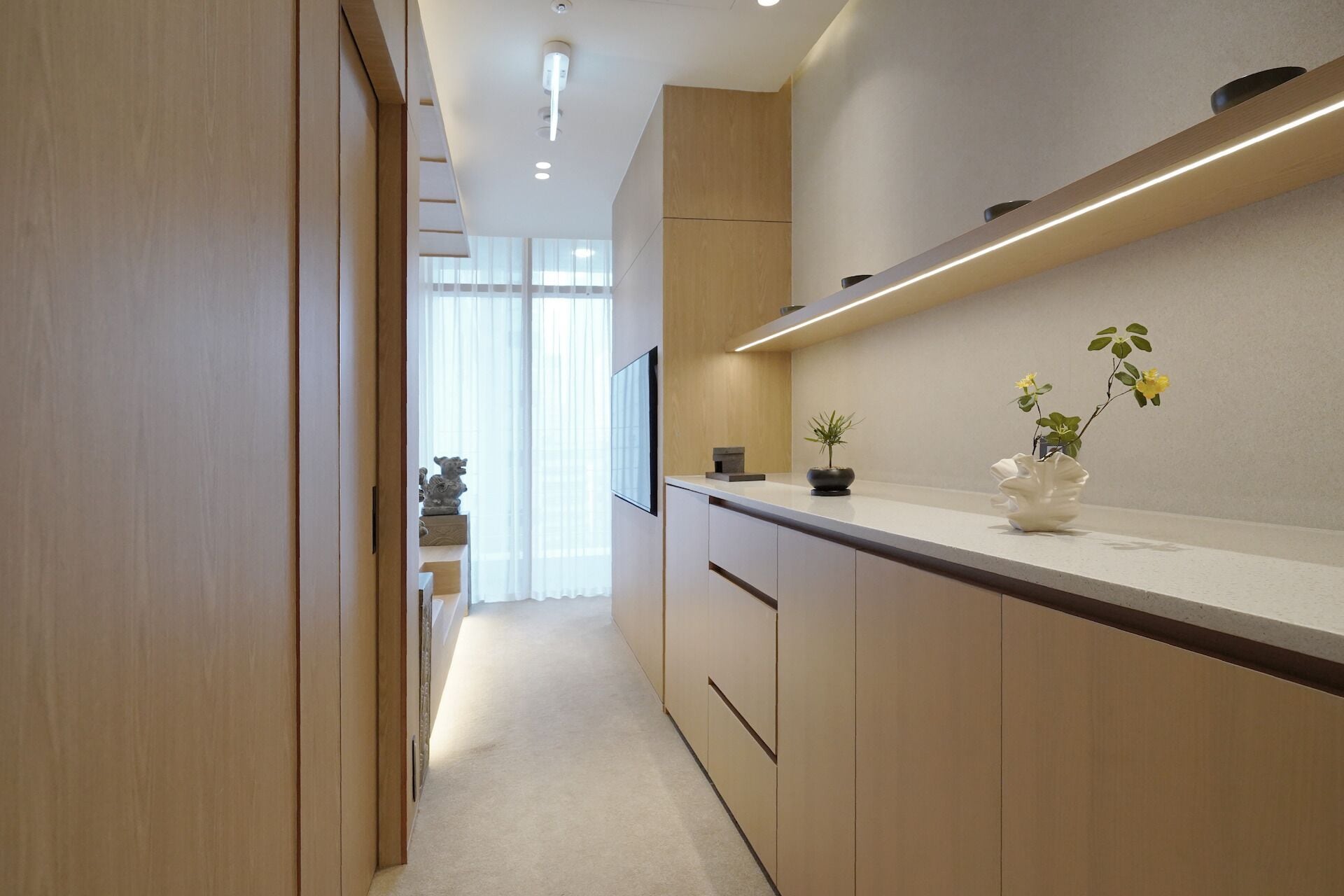 A modern kitchen with wooden cabinets, a countertop with potted plants, and a built-in oven.