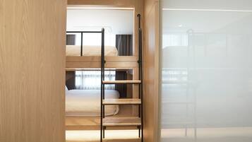 Dormitorio con literas, una escalera, una ventana con cortinas y una pared de madera.