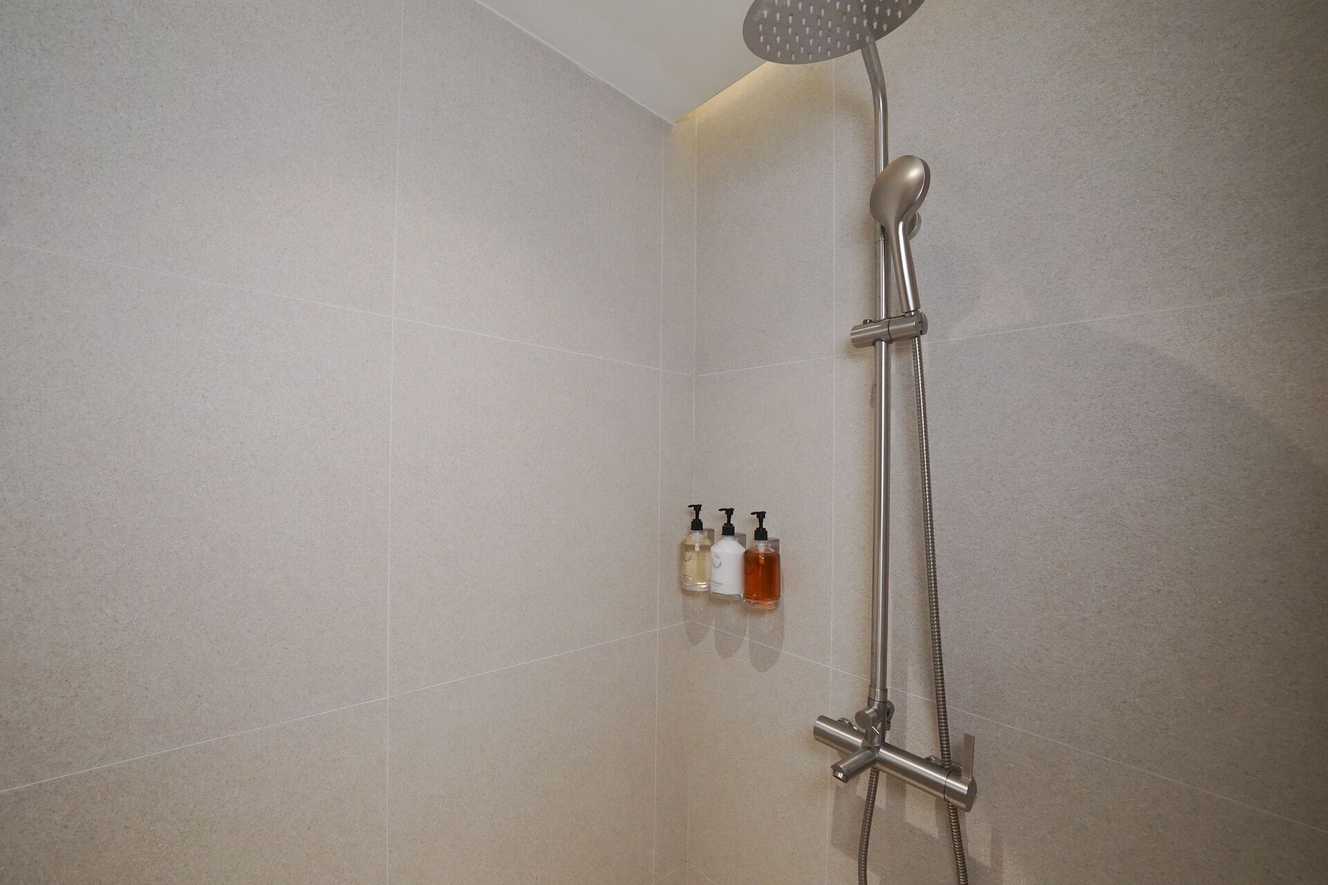 A shower with a handheld showerhead and a handheld shower attachment.
