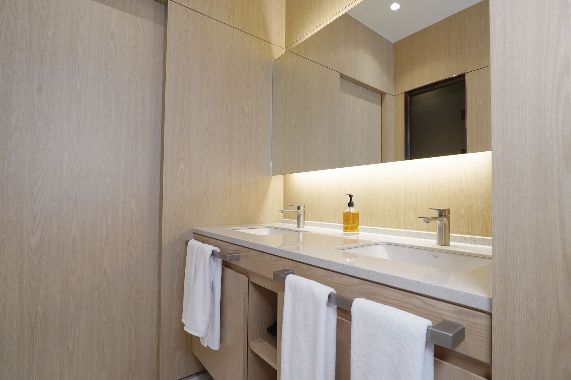 A modern bathroom with two sinks, a mirror, and a towel rack.