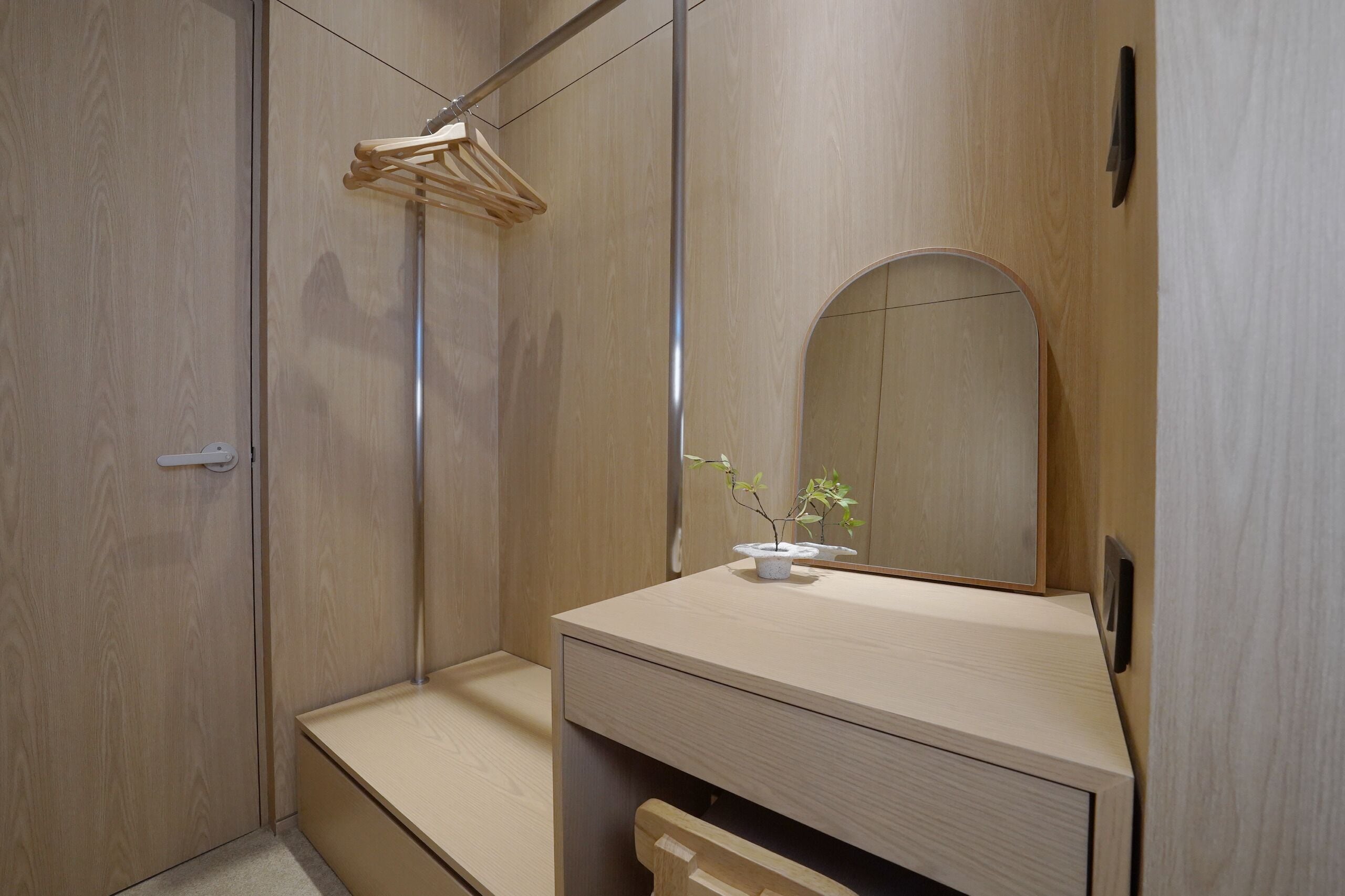 Een moderne badkamer met een houten wastafelmeubel, een spiegel en een hangende kledingrek.