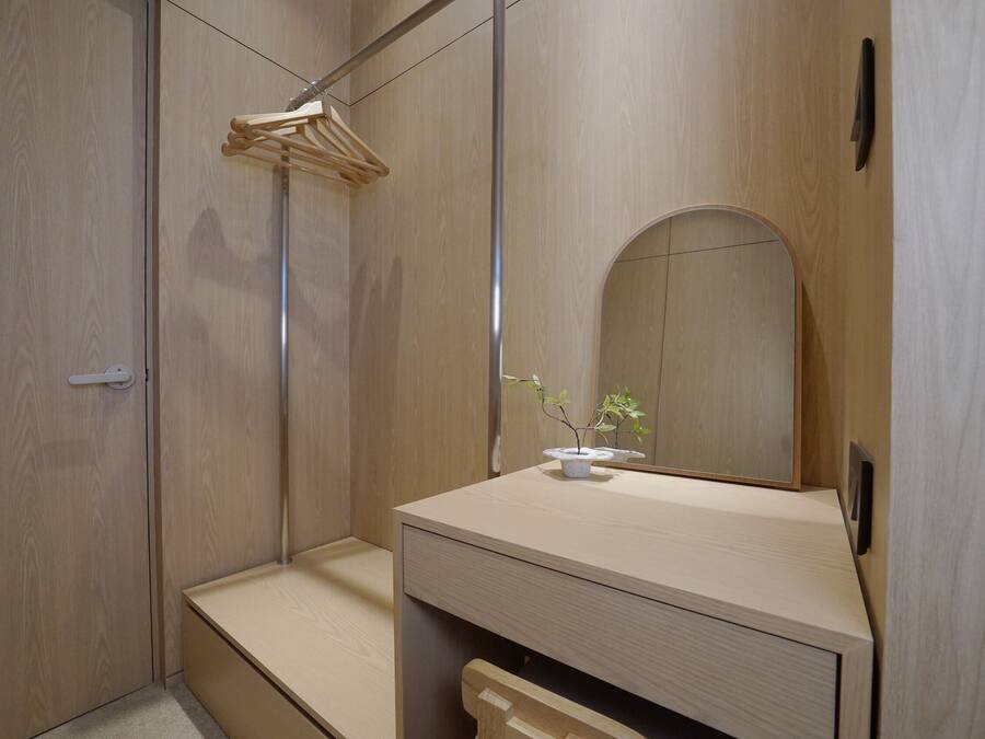 Een moderne badkamer met een houten wastafelmeubel, een spiegel en een hangende kledingrek.