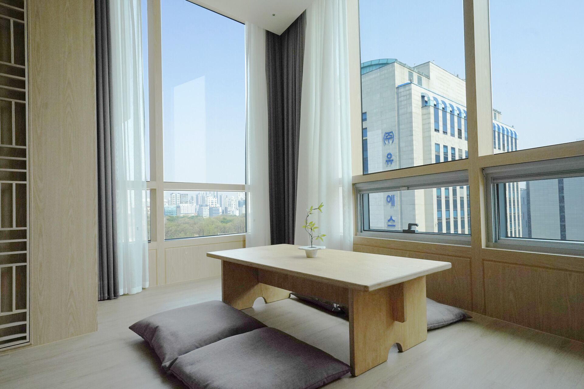 Une pièce avec de grandes fenêtres, une table en bois et deux coussins.