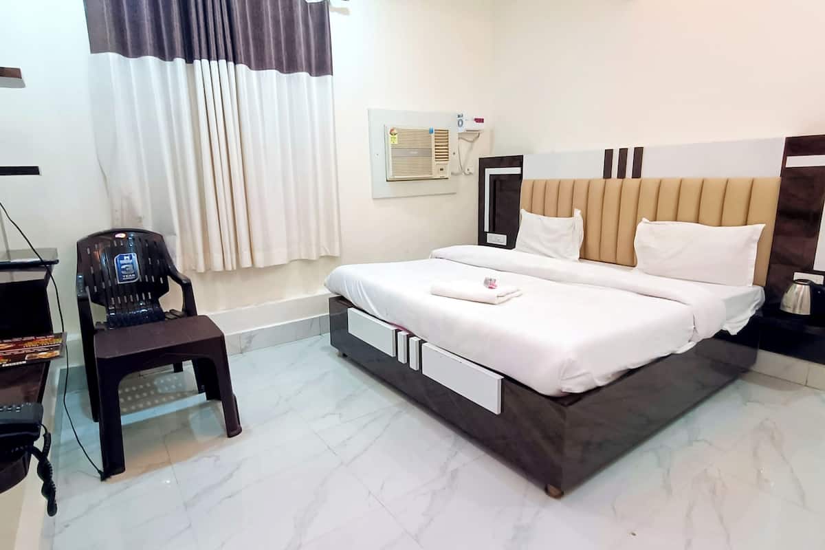 Habitación de hotel con cama, escritorio, teléfono, silla y unidad de aire acondicionado.