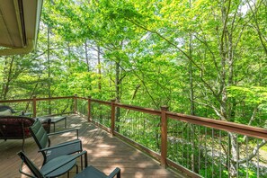 A wooden deck with chairs and a railing overlooking a forested area. - Vista Della Montagna (Lake Lure)
