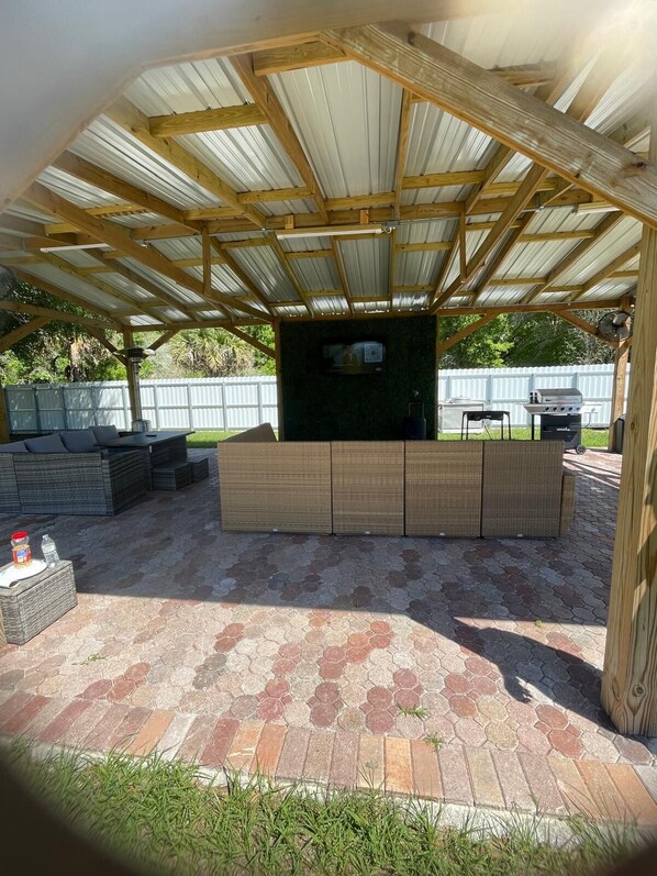 A covered outdoor area with a brick patio, a built-in seating area, and a grill. - Perfect 3-bedroom mobile home in nature paradise (Okeechobee)