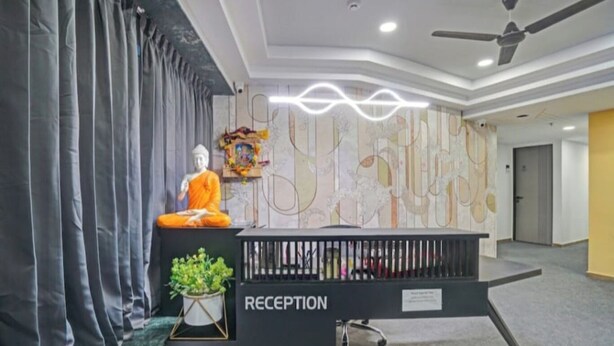 A reception desk with a 'RECEPTION' sign, a Buddha statue, and a wall with abstract art.