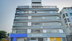 A multi-story building with a 'ROOMS' sign at the top, 'SAARTHI' and 'ARABIA MEDICAL SYSTEMS' on the ground floor, and a blue awning.