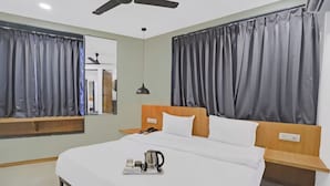 A hotel room with a bed, bedside tables, a ceiling fan, and curtains.