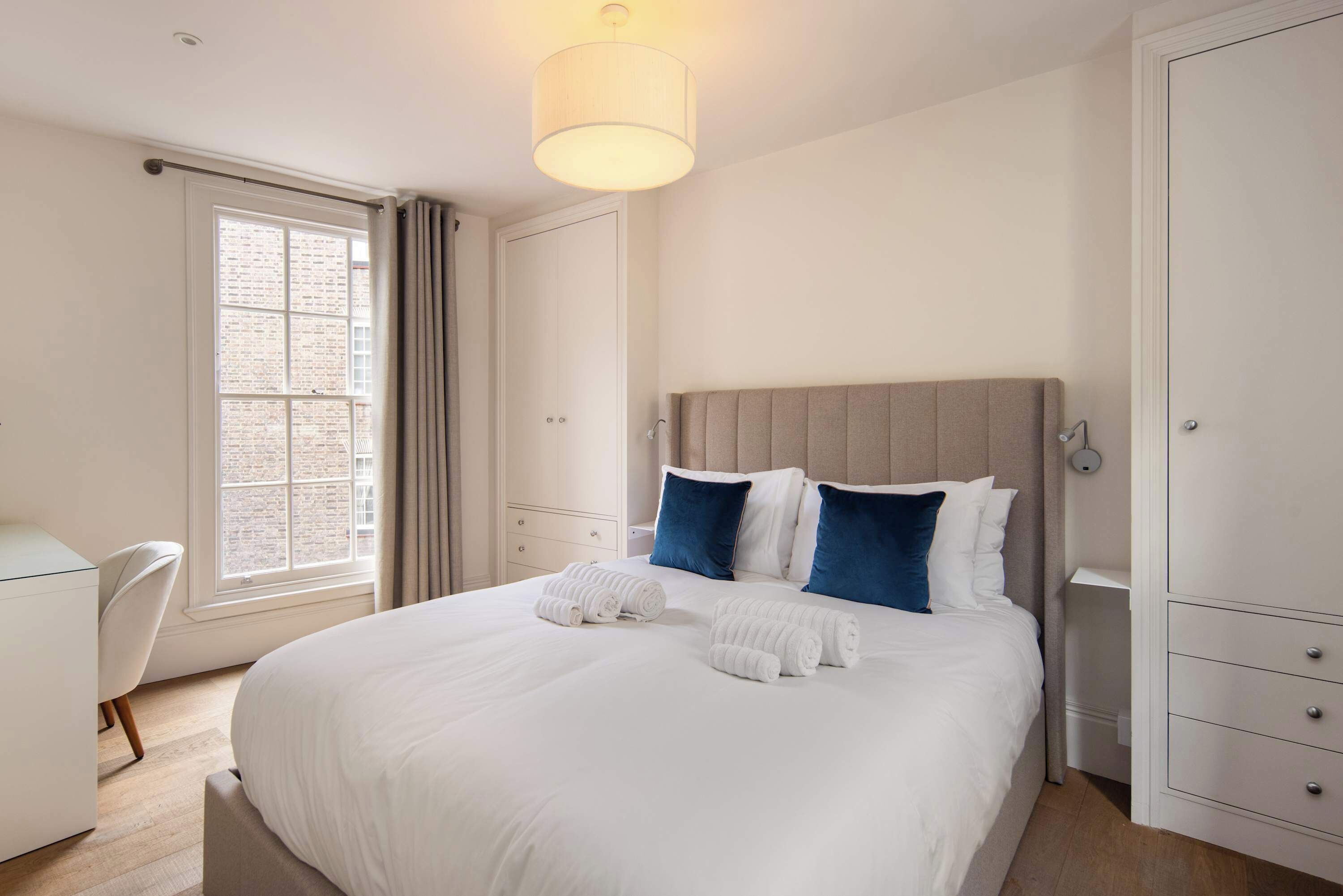 Une chambre d’hôtel avec un grand lit, un bureau, une chaise et une fenêtre avec des rideaux.