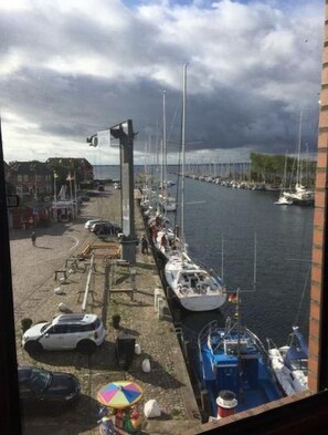A marina with boats docked, a pedestrian walkway, and a view of the water. - Ferienwohnung in Orth auf Fehmarn (Fehmarn)