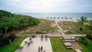 Eine Terrasse mit Sitzgelegenheiten im Freien, einer Flagge und Blick auf den Strand.