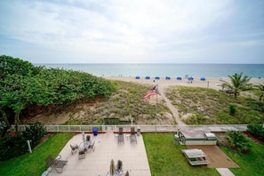 Eine Terrasse mit Sitzgelegenheiten im Freien, einer Flagge und Blick auf den Strand.